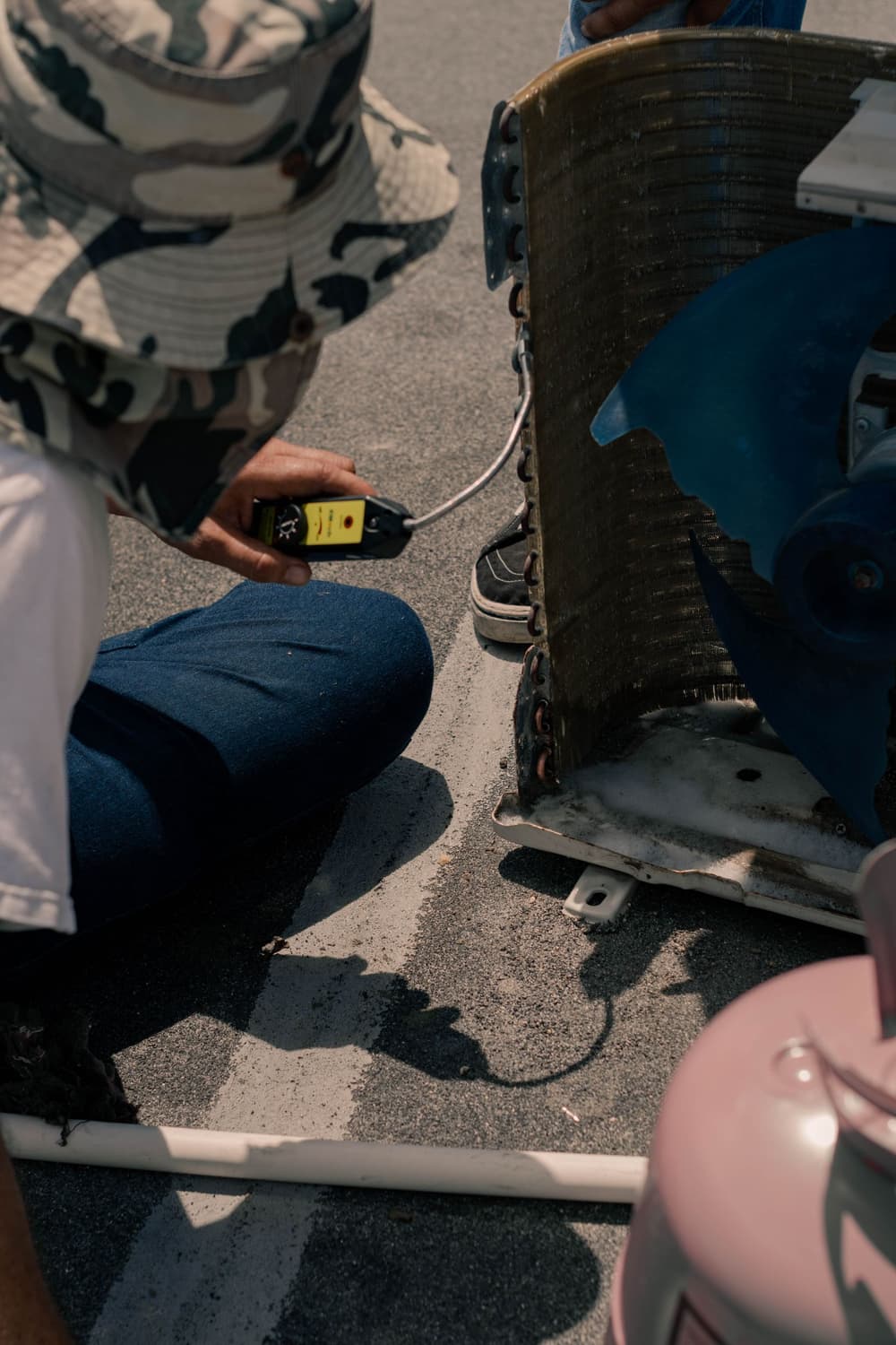 Technician testing an AC unit with a multimeter outdoors