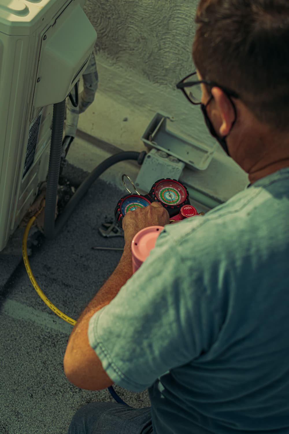 Gloved hands reading refrigerant gauges on an AC service call