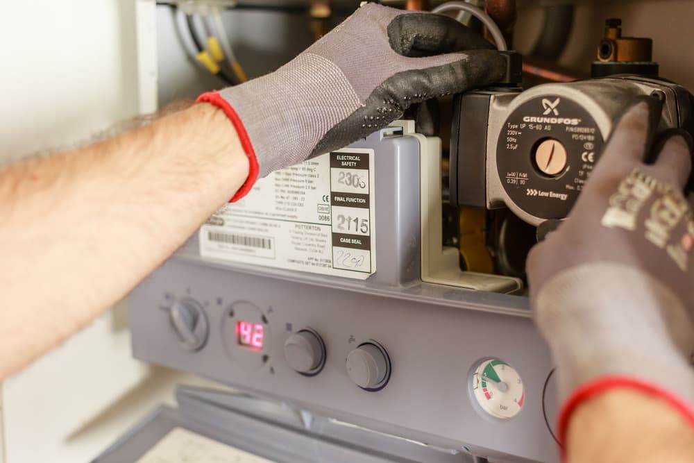 Gloved hands working on a heating system pump