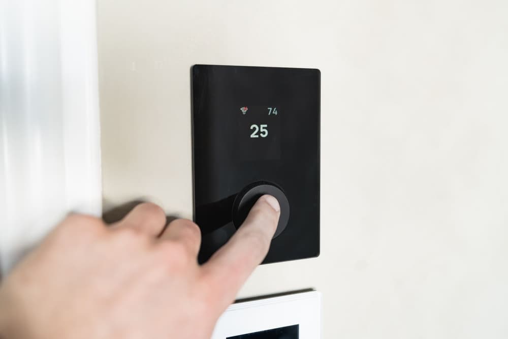 Finger pressing a black wall thermostat